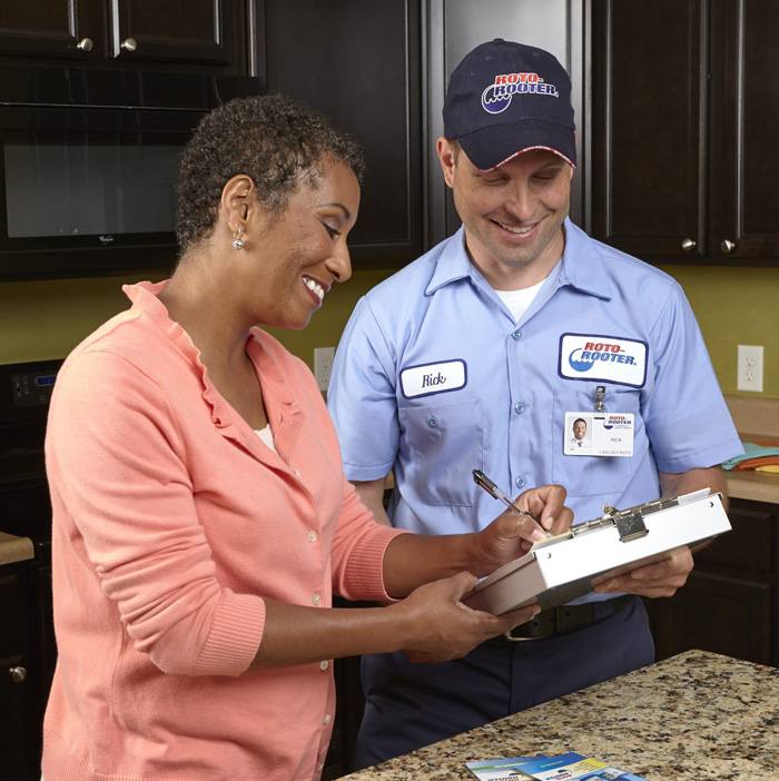 Roto-Rooter technician and customer smiling and signing