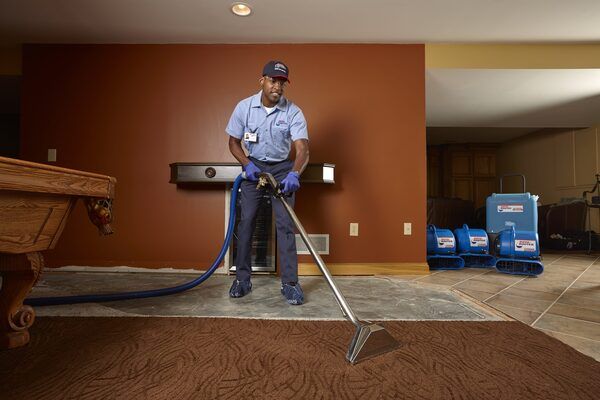 Water restoration basement extracting a tech Water Restoration expert extracting water while smiling