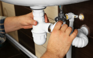 Plumbing Technician examining sink drain and opening it up