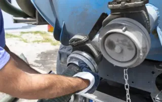 Roto-Rooter Plumber hooking up septic tank pumping pipe at the back of the truck