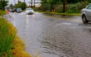 Flooding on the main road of the neigborhood and cars trying to drive by