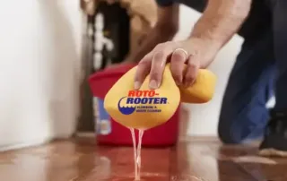 Homeowner cleaning up water damage with a yellow big sponge